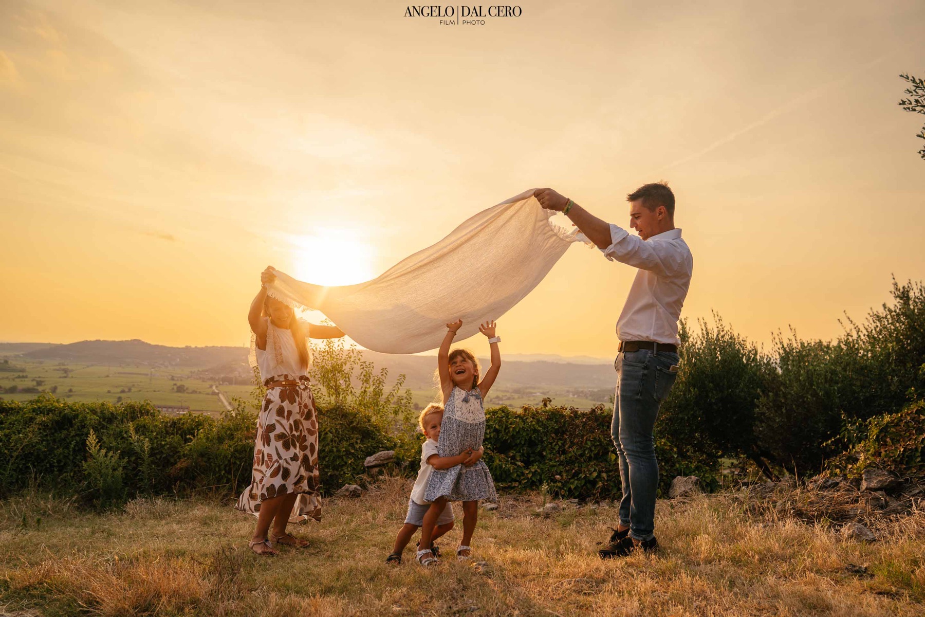 Una famiglia gioca con un telo nella luce del tramonto